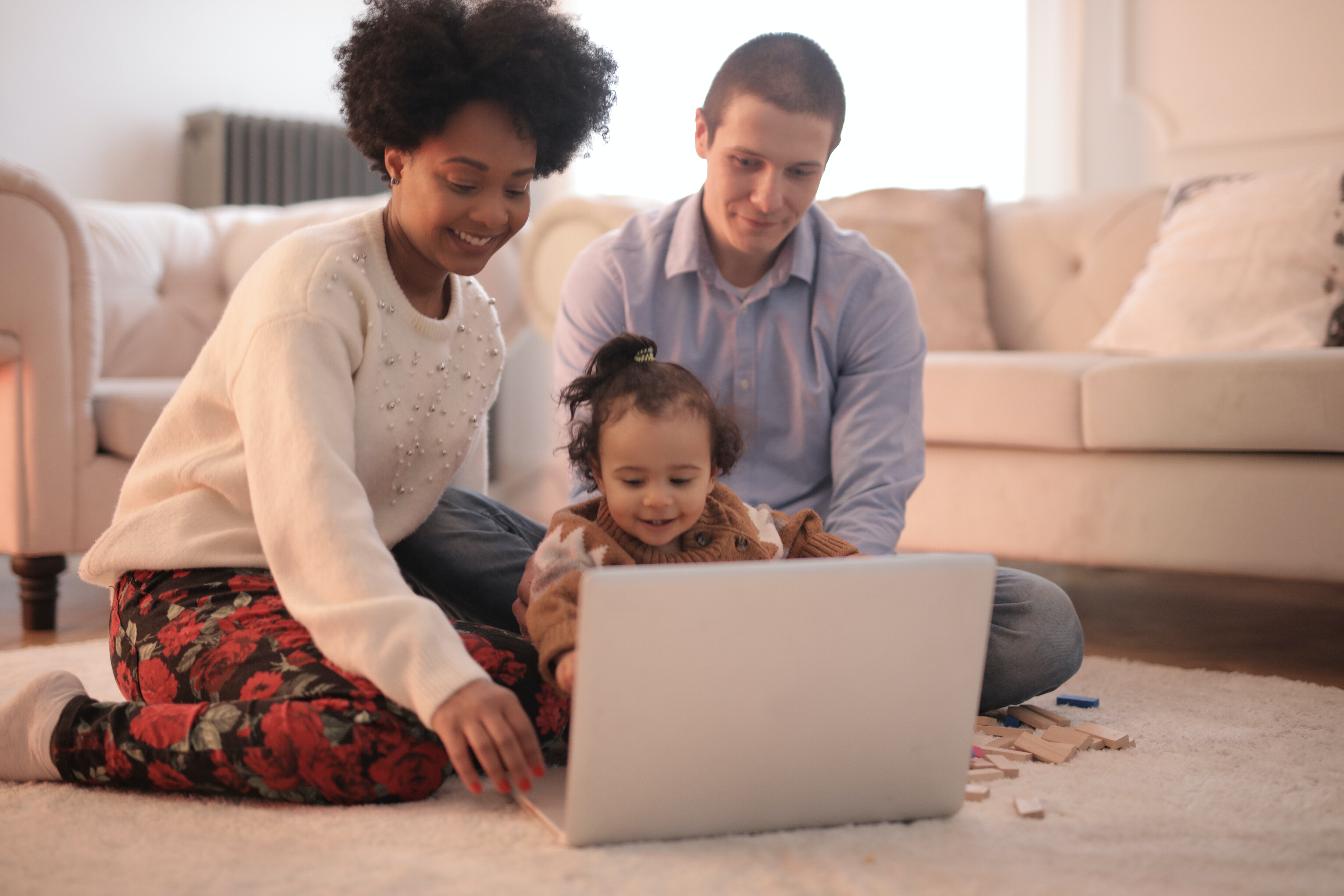 Photo of a Family Sitting on Floor While Using Laptop