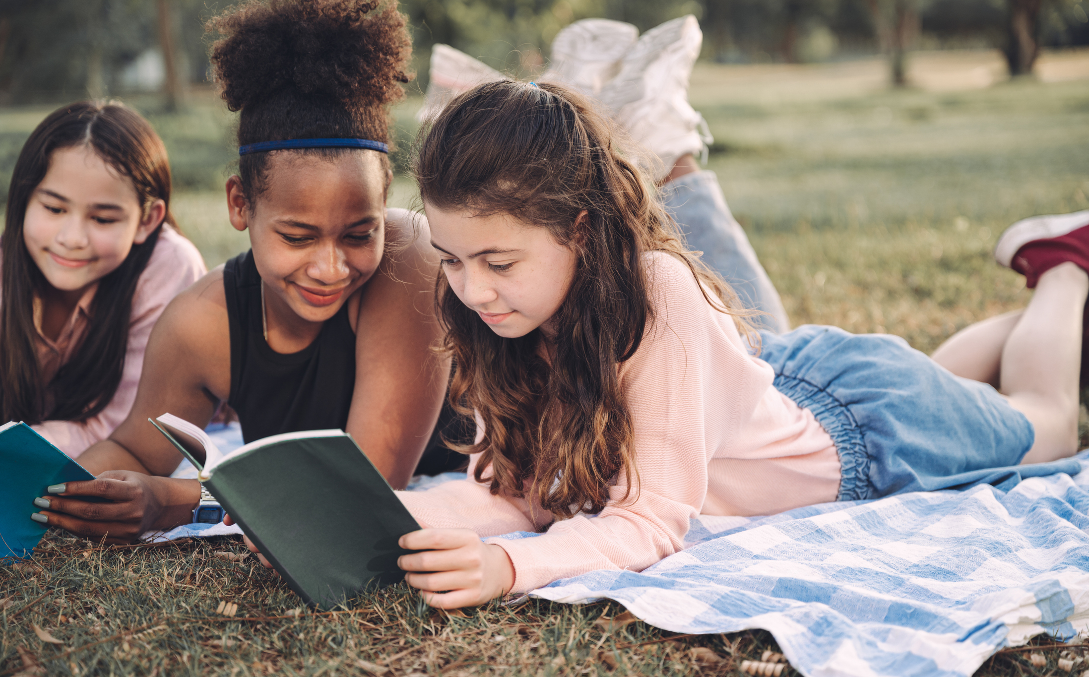 Tweens reading on a field 