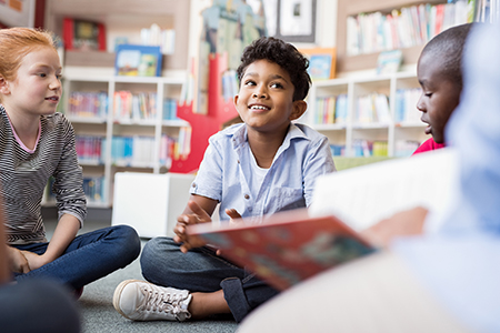 Child sitting in a circle with other children discussing a book