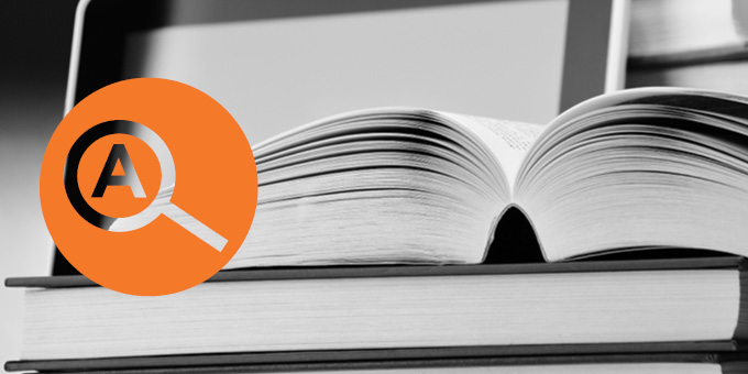 Black and white photo of an open book atop a stack of books