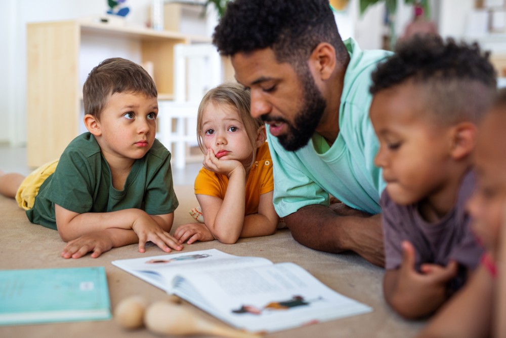 Person reading to a group of children on the floor