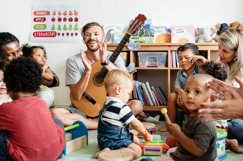 A person with a guitar who is clapping with a group of children