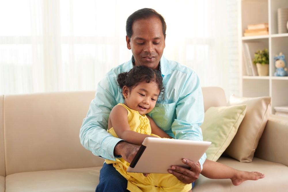 A person holding a child and looking at a tablet