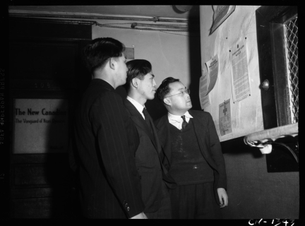 Japanese Canadian men reading document posted by R.C.M.P