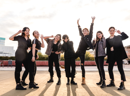 a group of teens dressed in black pose in a public square