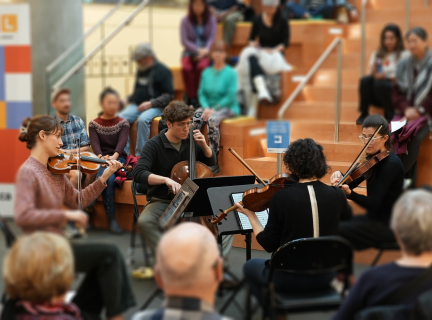 A group of classical musians playing on the grand staircase at VPL.