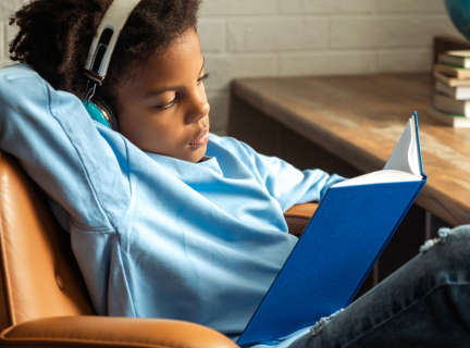 Kid with headphones on reading a book