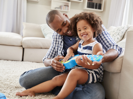 Parent and child smile and play ukulele