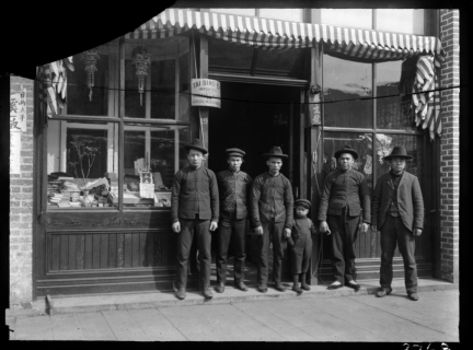 Chinese men and small boy in front of Tai Sing Co., Importers and Wholesale Dealers, General Merchandise.