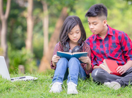A child reading with a teenager on the grass