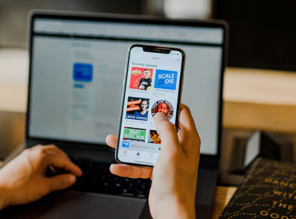 a phone with apple podcasts in front of a computer