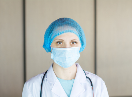 a healthcare worker wearing scrubs, a hair net, and a medical face mask.