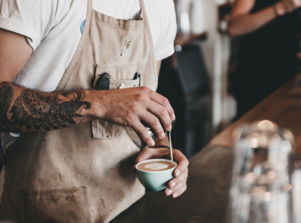 person pouring frothed milk into a cup of coffee