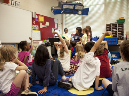 teaching assistant in classroom surrounded by students