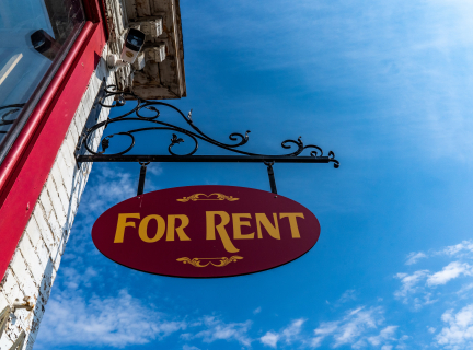 a for rent sign hangs off the side of a brick building