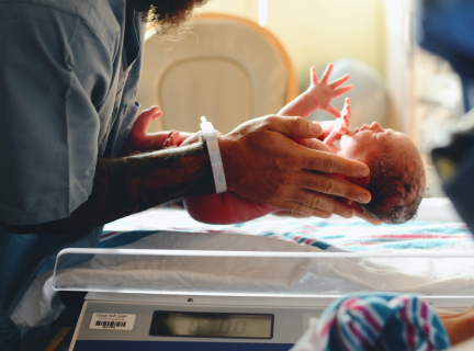 a healthcare worker places a newborn baby on a medical scale