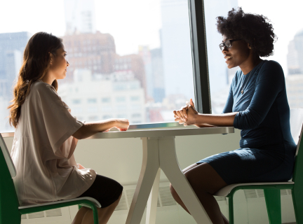 two women at a table having a conversation in a business setting