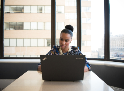 a woman sits at a table using a laptop computer in a professional setting.