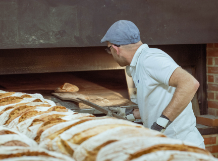 man putting bread into an oven