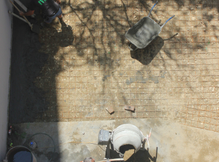 white plastic bucket filled with concrete being spread onto ground