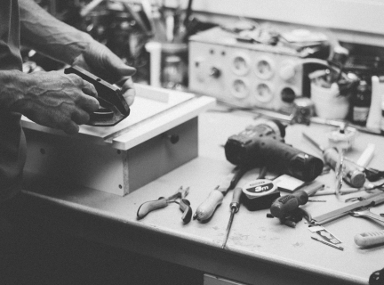 grayscale photo of person standing beside power tools on table