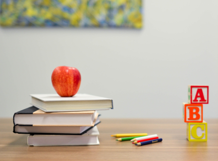 Photograph of books, an apple and alphabet blocks