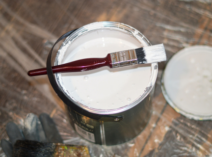 an open bucket of paint with a paint brush resting on top