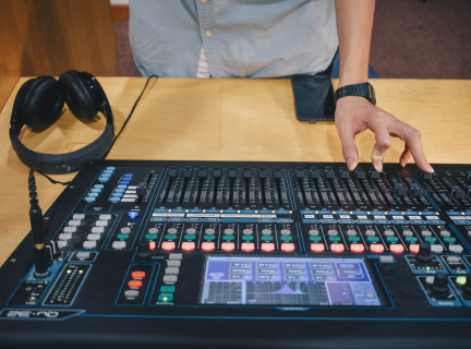 a person makes an adjustment on a sound mixing board