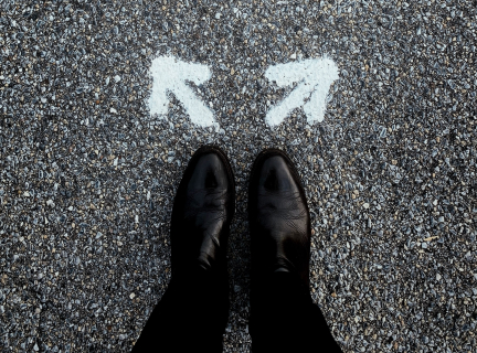 a pair of feet on pavement, with two arrows point in in different directions