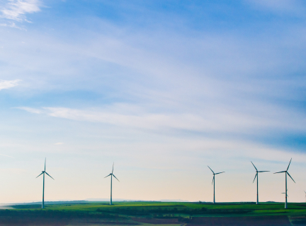 white windmills on green grass field under white clouds and blue sky