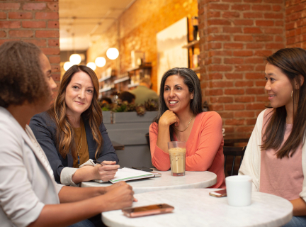 four women conducting a business meeting in a coffee shop.