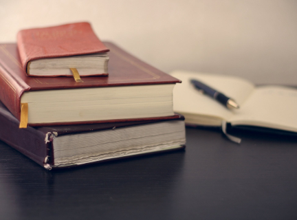 selective focus photography of three books beside opened notebook