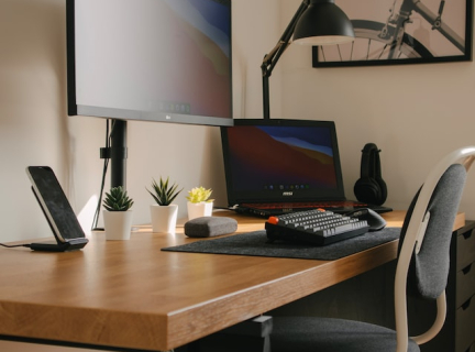 image of home office setup - desk, light, laptop, monitor, phone