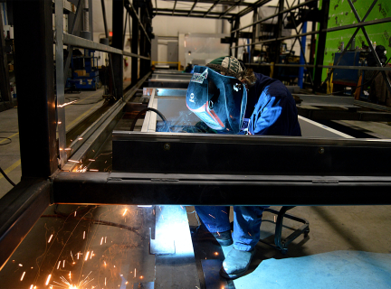 a person welding a large metal structure in a warehouse