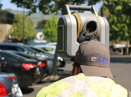 person using a land surveying device near some parked cars