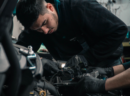 a man in a blue jacked repairing a vehicle