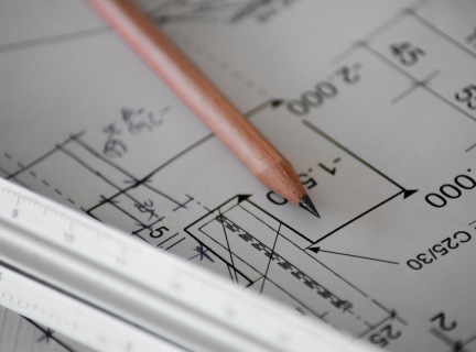 a close-up of a blueprint, a pencil, and a ruler.