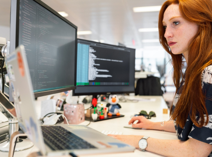 woman in green shirt sitting in front of computer