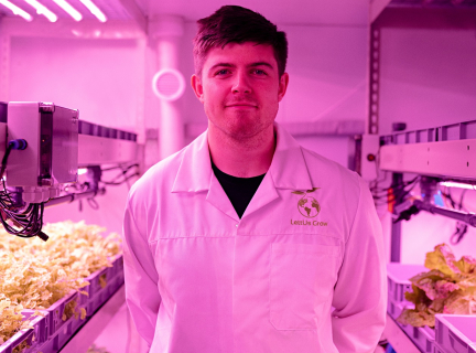 person in a white lab coat standing in an indoor food growing facility