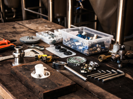 an assortment of plumbing tools are spread out on a wooden table. they include pliers, allen keys, and various specialized parts.