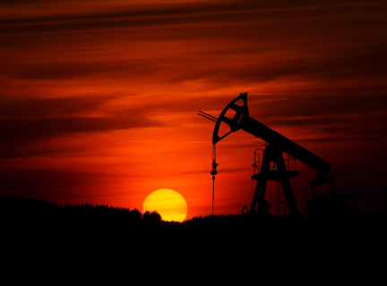 an oil pump jack with the sun setting behind it