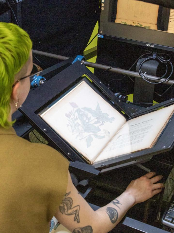 A person is using the Scribe digitization machine to scan a rare book