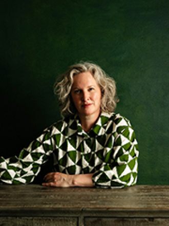 elee kraljii gardiner with left forearm on table with green background