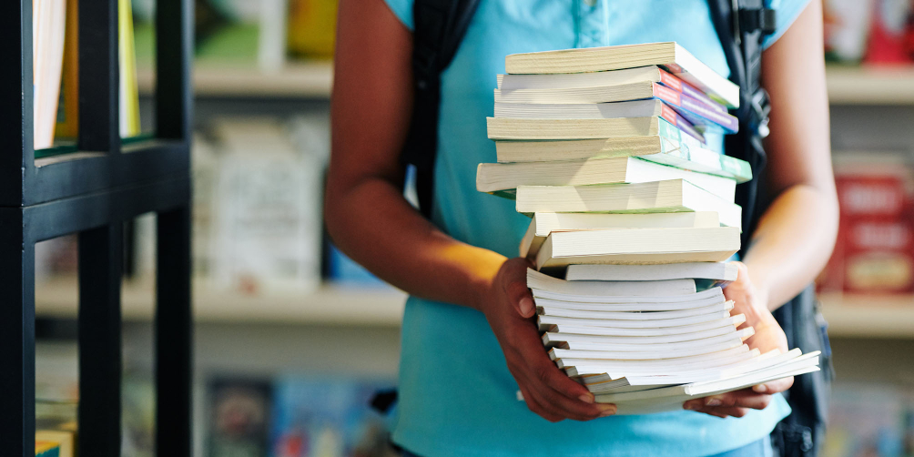 Person carries a stack of books