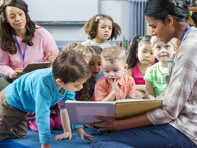 Two adults reading to a group of children